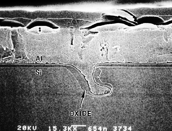 SEM image showing a different etching pit into the Si substrate. Note that oxide and Al were both deposited into the pit indicating that the etched pit occurred early in processing. (Courtesy Analytical Solutions).